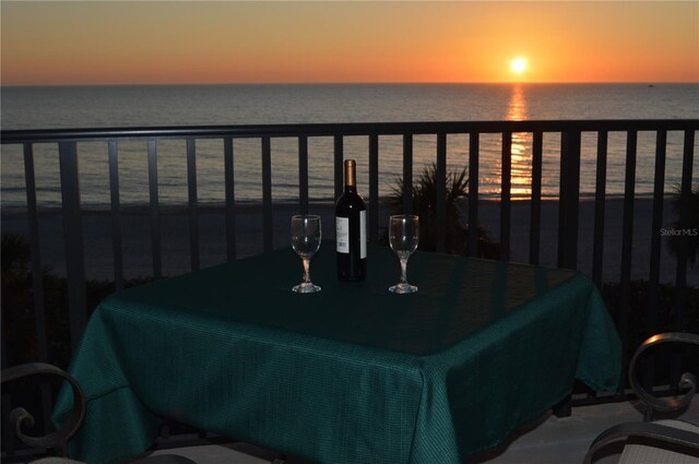 balcony at dusk featuring a water view