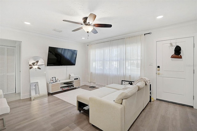 living room featuring ceiling fan, ornamental molding, and light hardwood / wood-style floors