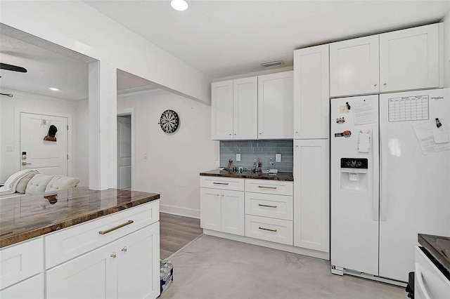 kitchen with white refrigerator with ice dispenser, backsplash, white cabinets, and wood counters