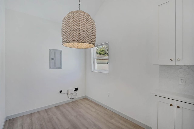 unfurnished dining area with electric panel and light hardwood / wood-style flooring