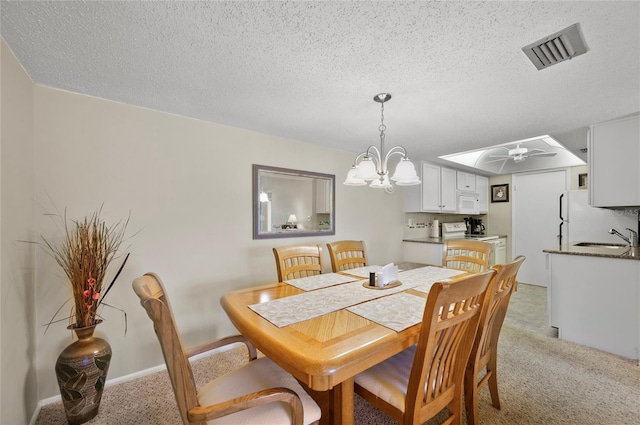 dining room featuring ceiling fan with notable chandelier, visible vents, a textured ceiling, and light colored carpet