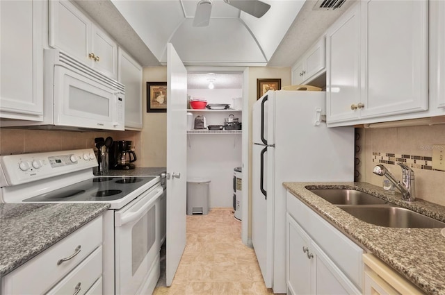 kitchen featuring white appliances, white cabinets, backsplash, vaulted ceiling, and a sink