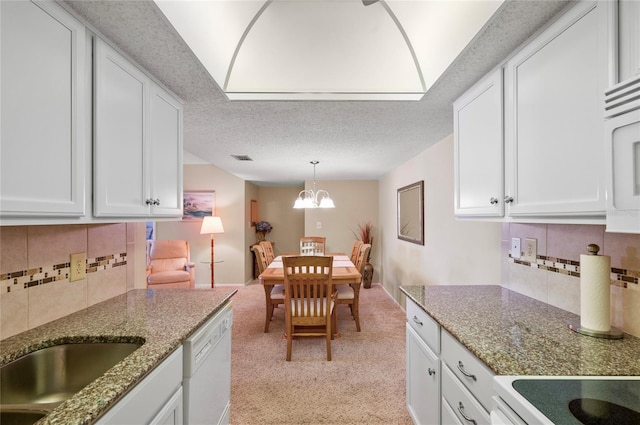 kitchen featuring a textured ceiling, light colored carpet, white appliances, white cabinets, and an inviting chandelier