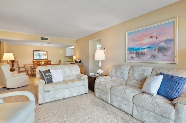 carpeted living room featuring visible vents, a chandelier, and a textured ceiling