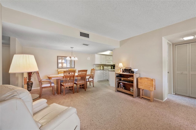 living room with light carpet, baseboards, visible vents, a textured ceiling, and a notable chandelier