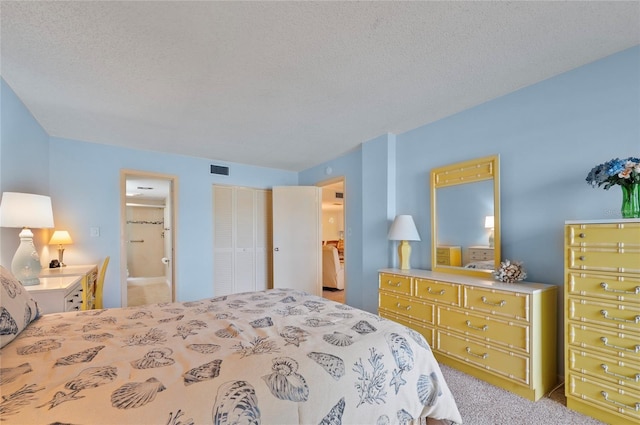 bedroom with a closet, visible vents, a textured ceiling, and ensuite bathroom