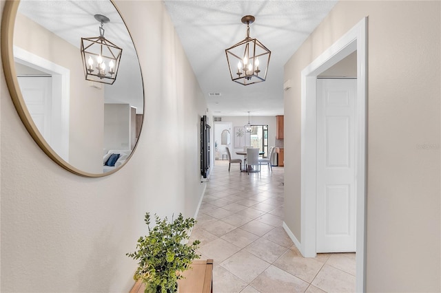 hall featuring light tile patterned flooring and a notable chandelier