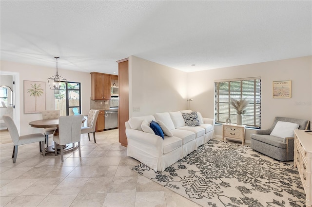 tiled living room featuring an inviting chandelier, plenty of natural light, and a textured ceiling