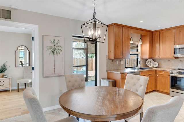 kitchen with sink, backsplash, a notable chandelier, and appliances with stainless steel finishes