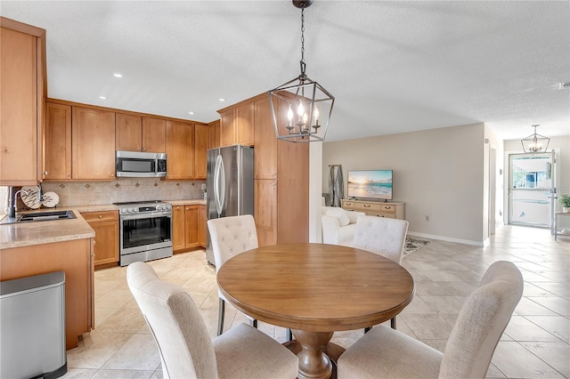 tiled dining space featuring a chandelier, sink, and a textured ceiling