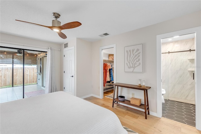 bedroom featuring hardwood / wood-style floors, a walk in closet, access to outside, ensuite bath, and a closet