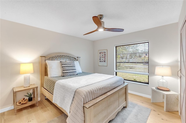 bedroom featuring ceiling fan, light hardwood / wood-style floors, and a textured ceiling