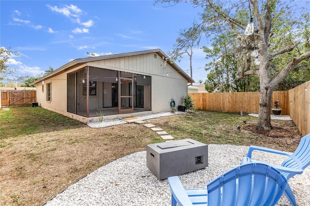 back of house with a patio, a sunroom, a lawn, and a fire pit