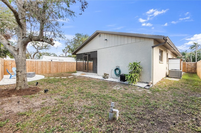 back of property with central AC unit and a lawn