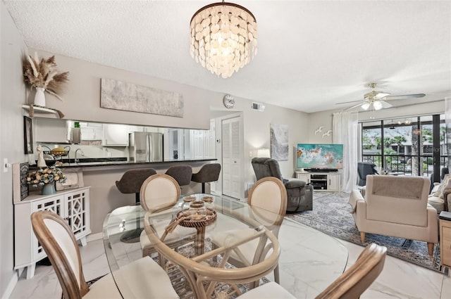 dining space featuring ceiling fan with notable chandelier, sink, and a textured ceiling