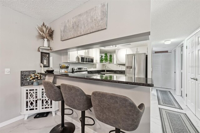 1515 Forrest Nelson Blvd Unit Q205, Port Charlotte, FL 33952 - kitchen featuring stainless steel appliances, marble finish floor, a sink, white cabinets, and a peninsula