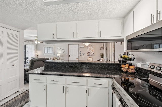 1515 Forrest Nelson Blvd Unit Q205, Port Charlotte, FL 33952 - kitchen with appliances with stainless steel finishes, a peninsula, a textured ceiling, white cabinets, and dark stone counters