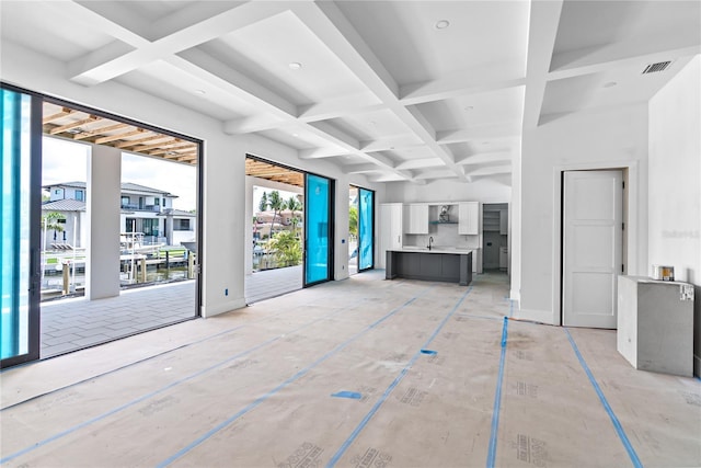 unfurnished living room with coffered ceiling, sink, and beam ceiling