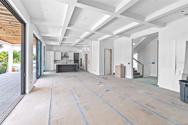 unfurnished living room featuring coffered ceiling and beam ceiling