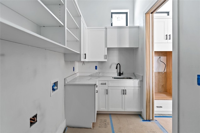 kitchen featuring light stone countertops, sink, and white cabinets