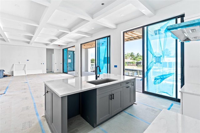 kitchen with coffered ceiling, sink, gray cabinetry, beam ceiling, and a kitchen island with sink