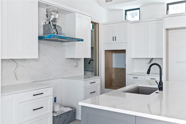 kitchen with backsplash, range hood, sink, and white cabinets