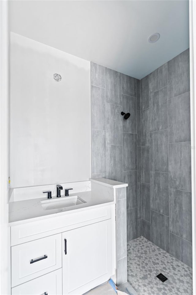 bathroom featuring tiled shower and vanity