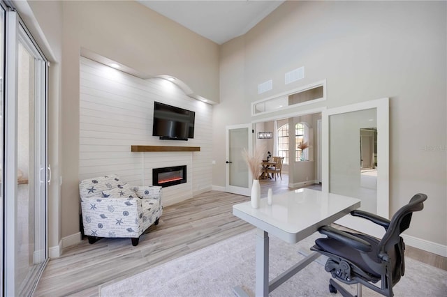 1314 Brambling Ct, Bradenton, FL 34212 - home office with wood finished floors, french doors, a glass covered fireplace, baseboards, and a towering ceiling