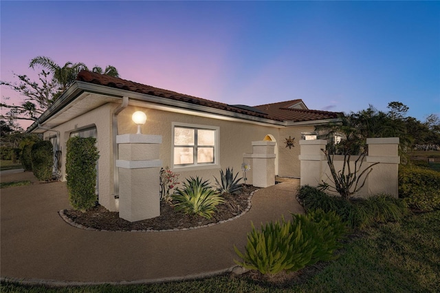 view of front facade featuring a garage, a tiled roof, and stucco siding