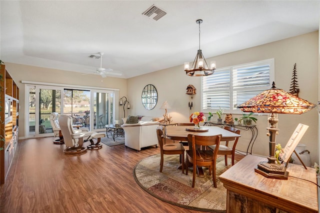 dining area featuring ceiling fan with notable chandelier, vaulted ceiling, wood finished floors, and visible vents