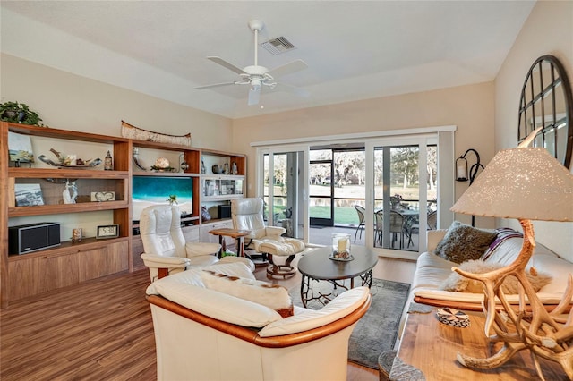 living area with a ceiling fan, visible vents, and wood finished floors