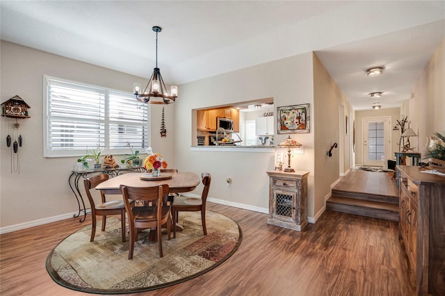 dining room with a notable chandelier, baseboards, and wood finished floors