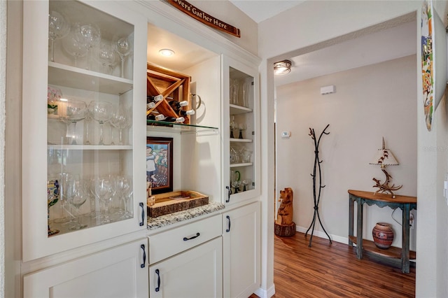 bar featuring indoor wet bar, wood finished floors, and baseboards