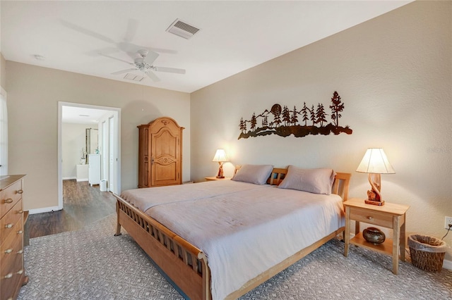 bedroom with visible vents, ensuite bathroom, ceiling fan, wood finished floors, and baseboards