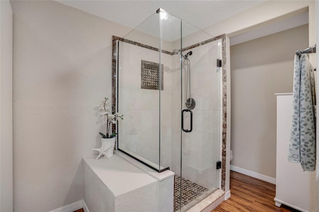 full bathroom with a shower stall, baseboards, and wood finished floors