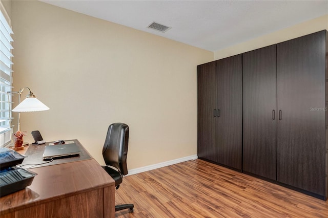 office with light wood-style flooring, visible vents, and baseboards