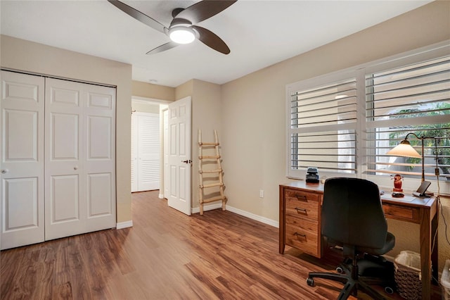 office space featuring a ceiling fan, baseboards, and wood finished floors