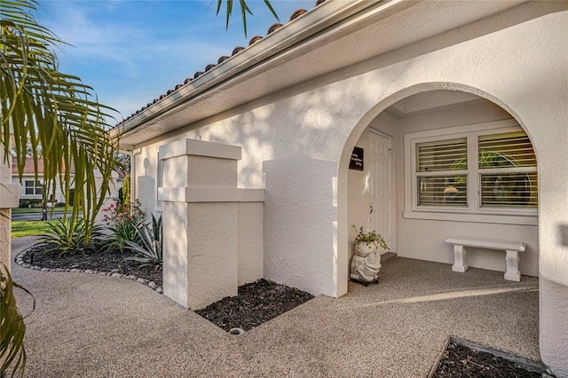 property entrance featuring a tiled roof and stucco siding