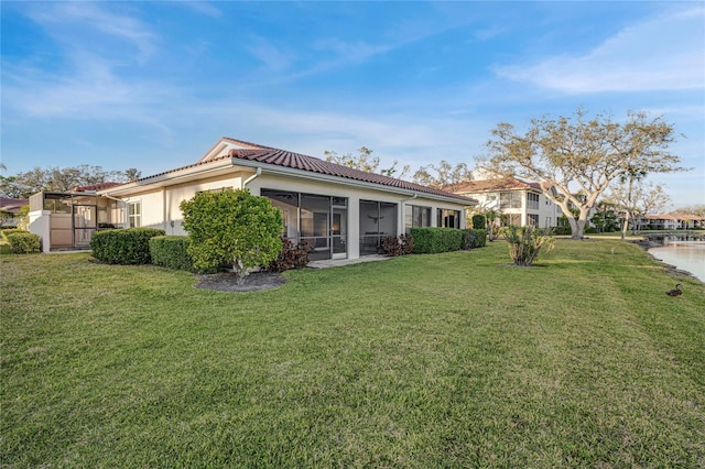 back of house featuring a yard, a tile roof, and a sunroom