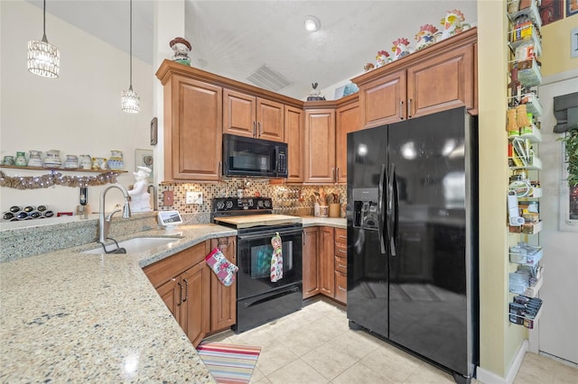 kitchen with pendant lighting, tasteful backsplash, sink, black appliances, and light stone countertops