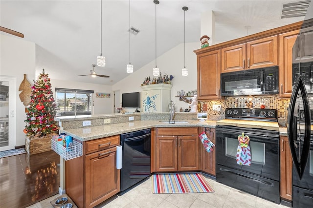 kitchen featuring sink, backsplash, hanging light fixtures, light stone counters, and black appliances