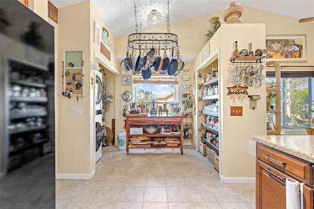 kitchen featuring light stone counters, wine cooler, light tile patterned flooring, decorative light fixtures, and vaulted ceiling