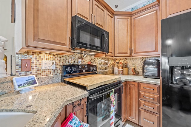 kitchen featuring light stone counters, tasteful backsplash, and black appliances