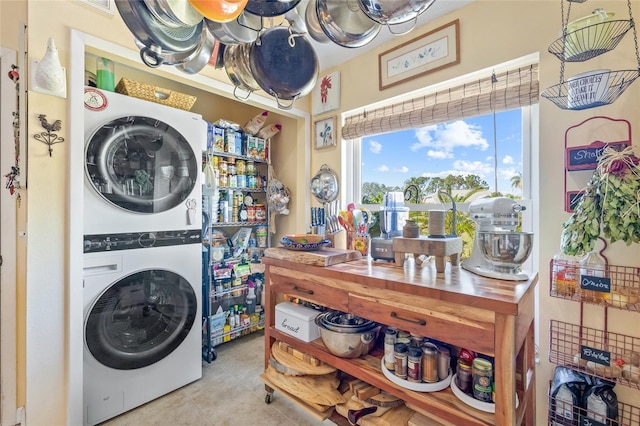 laundry room with light tile patterned flooring and stacked washer / drying machine