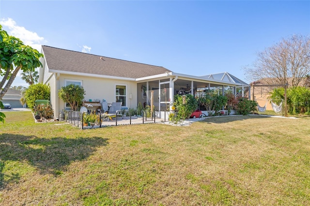 rear view of property featuring a lawn, a sunroom, and a patio