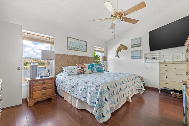 bedroom with vaulted ceiling, dark wood-type flooring, ceiling fan, and a textured ceiling