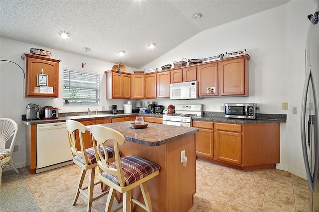 kitchen with lofted ceiling, a breakfast bar area, a center island, a textured ceiling, and stainless steel appliances