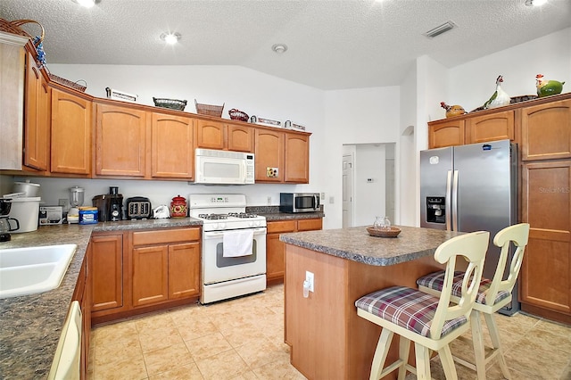 kitchen featuring lofted ceiling, sink, a kitchen bar, a center island, and stainless steel appliances