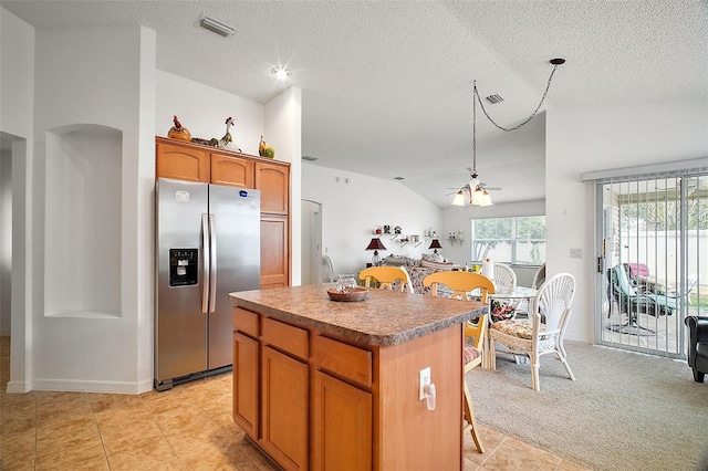 kitchen with vaulted ceiling, a kitchen island, stainless steel fridge, light carpet, and a textured ceiling