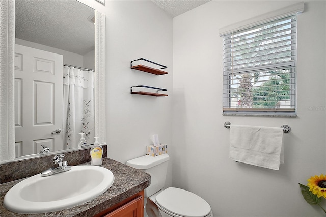 bathroom with vanity, toilet, and a textured ceiling